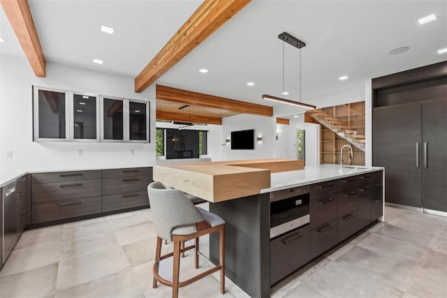 409 Fox Chapel Rd, Fox Chapel, PA 15238 - kitchen featuring beam ceiling, modern cabinets, glass insert cabinets, a breakfast bar, and light countertops