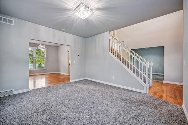 1523 Lori Ln, Hermitage, PA 16148 - unfurnished living room featuring a chandelier, carpet floors, stairs, baseboards, and wood finished floors