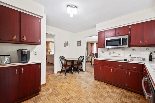 244 Elmtree Rd, New Kensington, PA 15068 - kitchen featuring stainless steel microwave, light countertops, red cabinetry, and tasteful backsplash