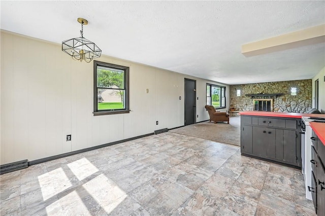 13035 State Highway 618, Conneaut Lake Cra, PA 16316 - kitchen with gray cabinets, open floor plan, a stone fireplace, light stone finish flooring, and pendant lighting