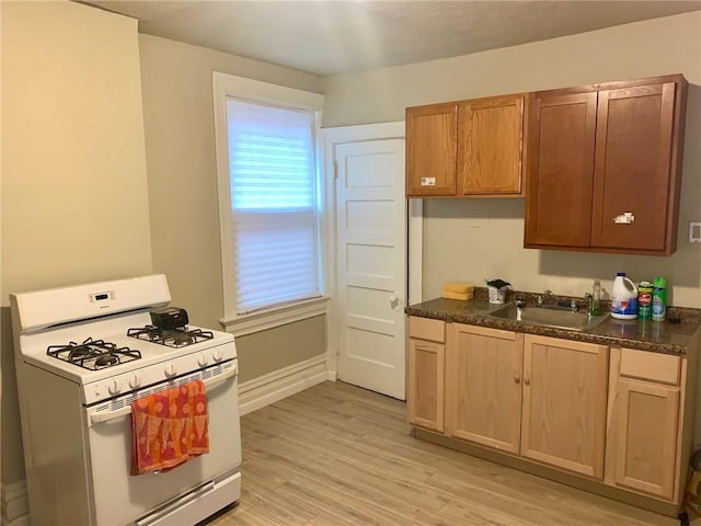 601 N Ave, Wilkinsburg, PA 15221 - kitchen with white range with gas cooktop, a sink, dark countertops, and light wood-type flooring