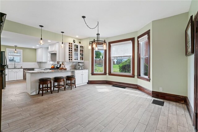 1622 Ridge Ave, Coraopolis, PA 15108 - kitchen with glass insert cabinets, light wood finished floors, a breakfast bar area, white cabinetry, and recessed lighting