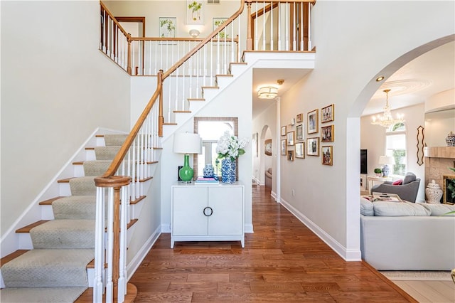 585 Agnes St, Hempfield Twp Wml, PA 15601 - staircase with arched walkways, wood finished floors, a chandelier, a high ceiling, and baseboards