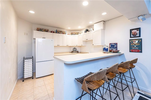 585 Agnes St, Hempfield Twp Wml, PA 15601 - kitchen with freestanding refrigerator, a peninsula, a kitchen breakfast bar, white cabinets, and recessed lighting