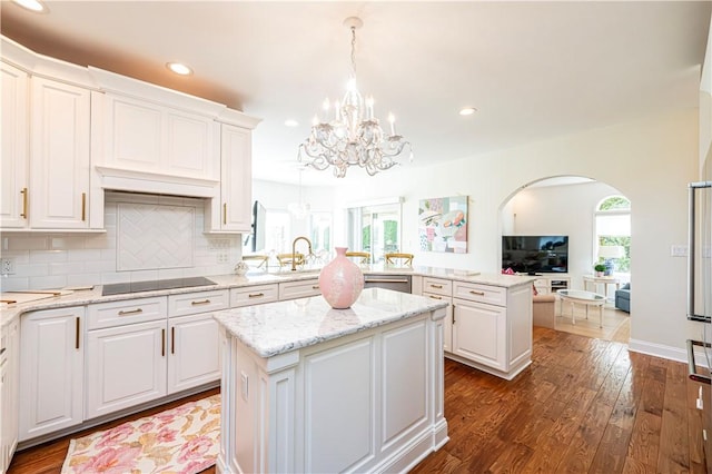 585 Agnes St, Hempfield Twp Wml, PA 15601 - kitchen featuring black electric stovetop, a chandelier, a kitchen island, arched walkways, and a peninsula