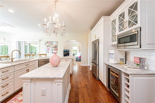 585 Agnes St, Hempfield Twp Wml, PA 15601 - kitchen with a sink, appliances with stainless steel finishes, beverage cooler, a kitchen island, and arched walkways