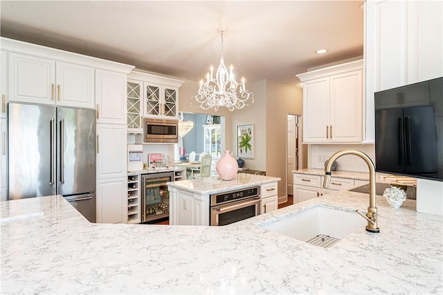 585 Agnes St, Hempfield Twp Wml, PA 15601 - kitchen with appliances with stainless steel finishes, wine cooler, a sink, a chandelier, and light stone counters