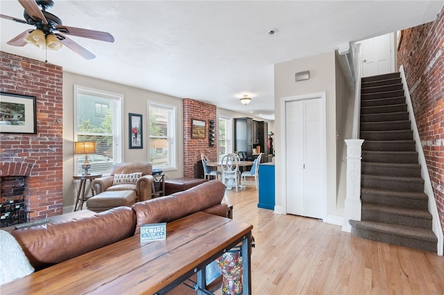 4232 Sherrod St, Lawrenceville, PA 15201 - living room with light wood-style flooring, stairway, a fireplace, ceiling fan, and brick wall