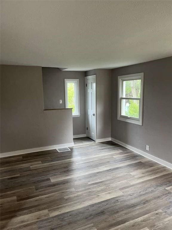 3309 Woodvue Dr, Whitehall, PA 15227 - empty room with healthy amount of natural light, baseboards, a textured ceiling, and dark wood-style flooring