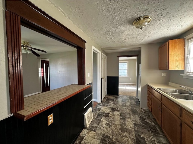 2310 Delaware Ave, New Castle/2Nd, PA 16105 - kitchen with a sink, baseboards, brown cabinetry, ceiling fan, and dark stone finish flooring