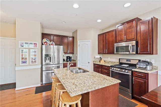 2282 Flint Dr, South Strabane, PA 15301 - kitchen with stainless steel appliances, a sink, light wood-style floors, a center island with sink, and light stone countertops