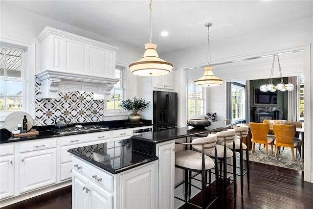506 Villa Dr, Peters Twp, PA 15367 - kitchen with stainless steel gas cooktop, black fridge with ice dispenser, a center island, backsplash, and dark wood finished floors