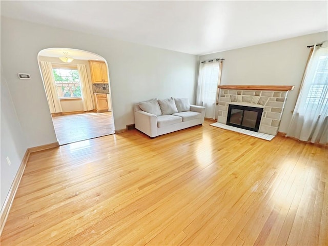 940 Warren Ave, New Castle/4Th, PA 16101 - living room with light wood-style flooring, arched walkways, a stone fireplace, and baseboards
