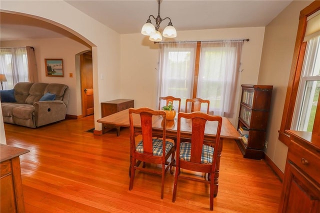 1265 Slippery Rock Rd, Liberty Twp, PA 16057 - dining room featuring a chandelier, arched walkways, light wood finished floors, and baseboards