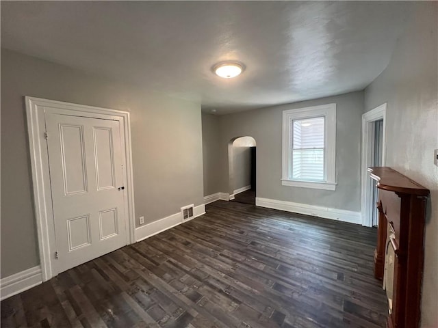 167 S 15th St, South Side, PA 15203 - unfurnished living room with arched walkways, dark wood-style floors, and baseboards