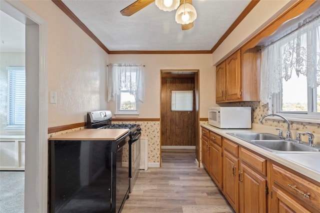 2238 Lucina Ave, Overbrook, PA 15210 - kitchen with white microwave, black gas range, light wood-style floors, light countertops, and ceiling fan