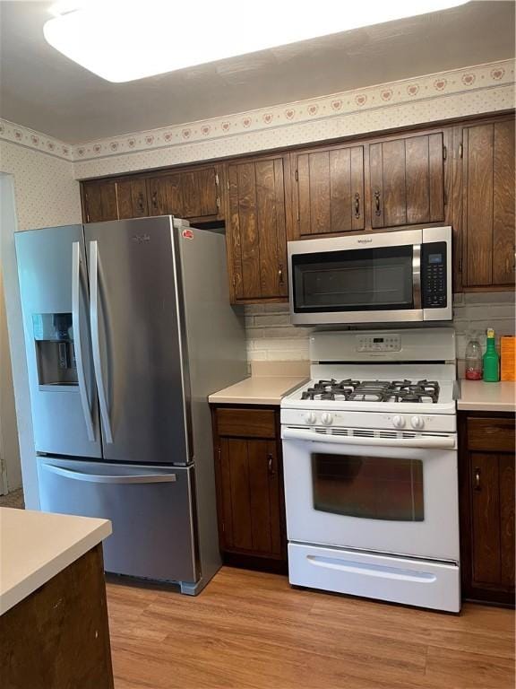 241 Willow Dr, Monroeville, PA 15146 - kitchen with appliances with stainless steel finishes, wallpapered walls, light countertops, dark brown cabinets, and light wood finished floors
