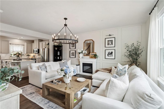 436 Greenwood Dr, North Strabane, PA 15317 - living area with dark wood-style floors, a chandelier, a decorative wall, and a glass covered fireplace
