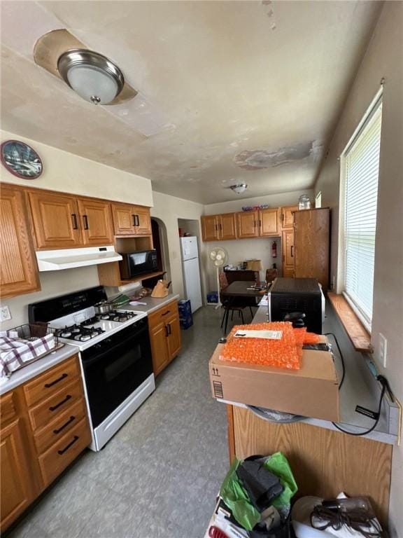2709 Leland St, Perry Hilltop, PA 15214 - kitchen with range with gas cooktop, under cabinet range hood, black microwave, arched walkways, and freestanding refrigerator