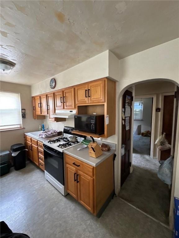 2709 Leland St, Perry Hilltop, PA 15214 - kitchen featuring black microwave, range with gas stovetop, arched walkways, under cabinet range hood, and brown cabinets