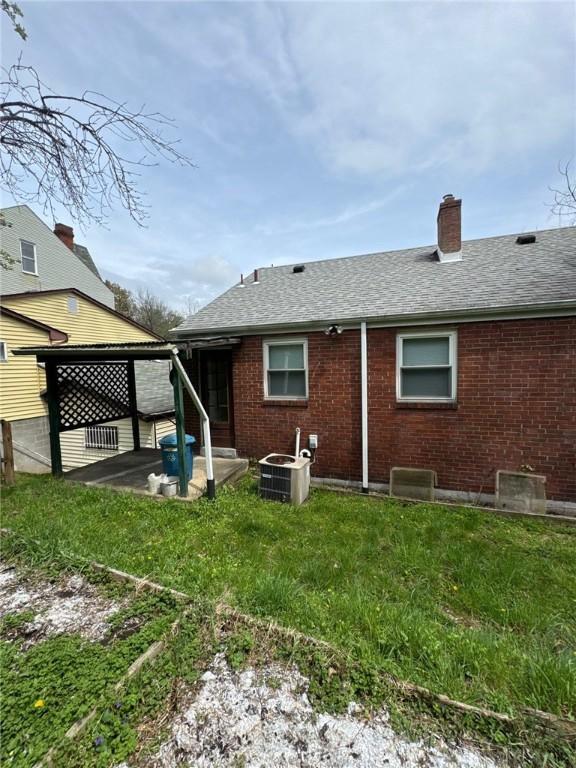 2709 Leland St, Perry Hilltop, PA 15214 - back of house featuring a patio, brick siding, a chimney, roof with shingles, and cooling unit