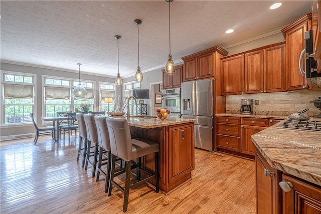 102 Maple Gln, Peters Twp, PA 15367 - kitchen with appliances with stainless steel finishes, crown molding, brown cabinetry, light stone countertops, and light wood-style flooring