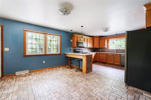 321 Green Acres Ln, Shenango Twp Law, PA 16101 - kitchen with stainless steel appliances, a peninsula, brick patterned floors, a kitchen bar, and light countertops