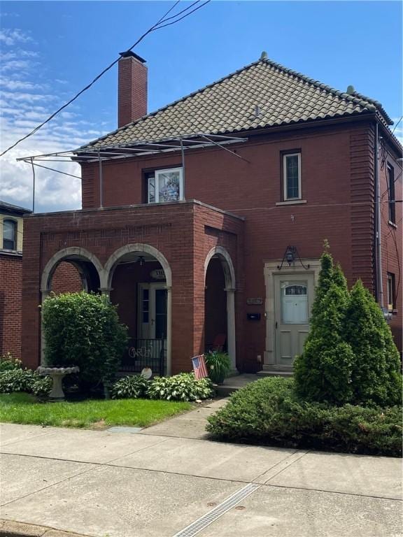 1218 6th Ave, Beaver Falls, PA 15010 - view of front of home featuring a tiled roof, brick siding, a chimney, and covered porch