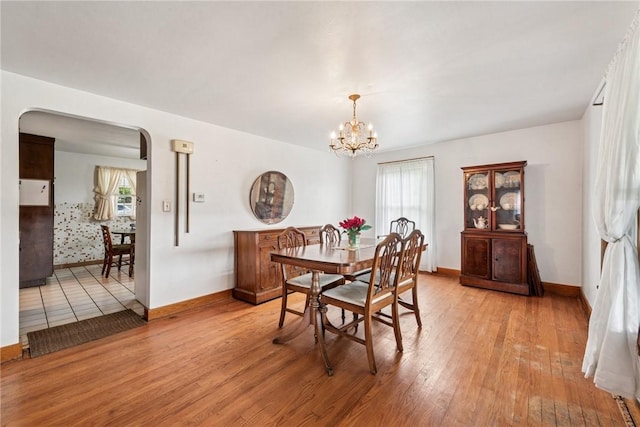 1068 Lakeview Dr, Unity Twp, PA 15650 - dining area with arched walkways, baseboards, light wood-style floors, and a chandelier