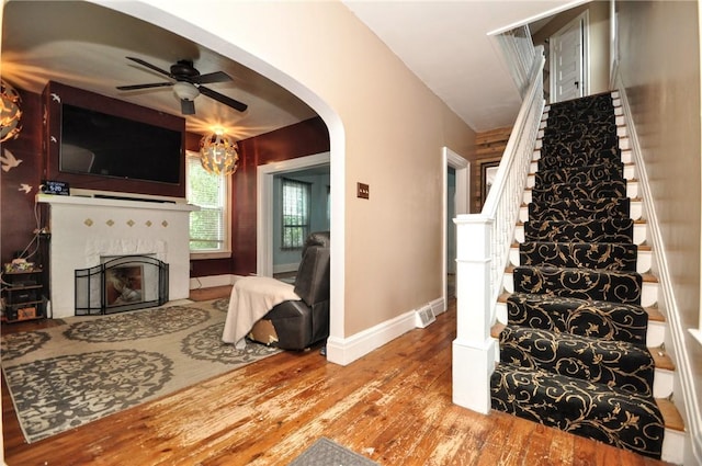 222 Orchard Ave, Canonsburg, PA 15317 - stairway featuring wood finished floors, a ceiling fan, a fireplace with flush hearth, baseboards, and arched walkways