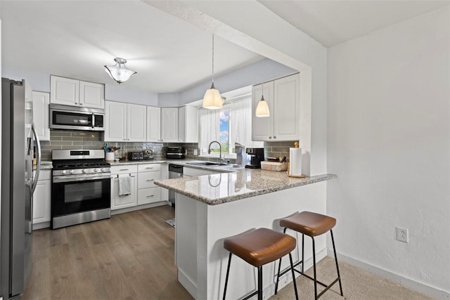 3050 S Park Rd, Bethel Park, PA 15102 - kitchen featuring stainless steel appliances, a sink, a peninsula, backsplash, and white cabinetry