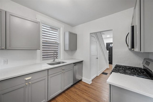 230 Linnview Ave, Carrick, PA 15210 - kitchen with appliances with stainless steel finishes, gray cabinetry, a sink, and light wood-style flooring