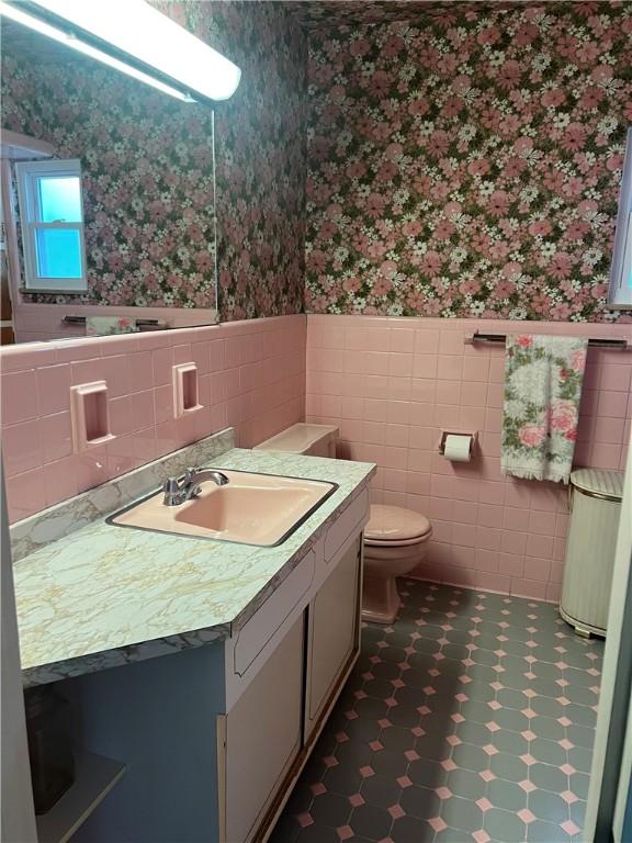 1929 Alcoa Dr, Arnold, PA 15068 - bathroom with wallpapered walls, wainscoting, vanity, tile walls, and tile patterned floors