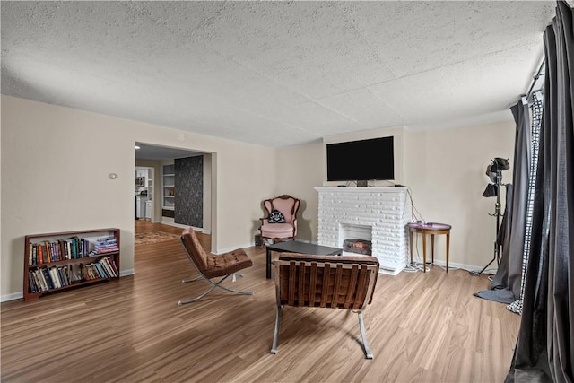 115 Frederick St, Mount Oliver, PA 15210 - living area with wood finished floors, a brick fireplace, baseboards, and a textured ceiling