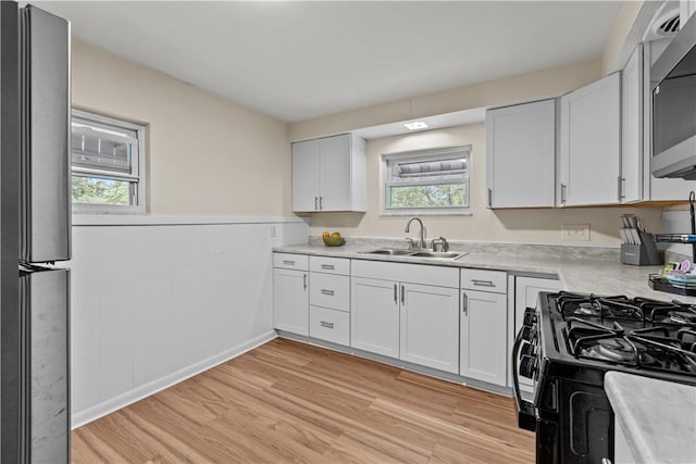 115 Frederick St, Mount Oliver, PA 15210 - kitchen featuring a sink, appliances with stainless steel finishes, light wood-type flooring, light countertops, and white cabinetry
