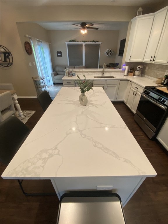 173 Rylie Dr, Lehigh Twp, PA 16037 - kitchen with stainless steel gas stove, a kitchen island, dark wood finished floors, a ceiling fan, and light stone countertops