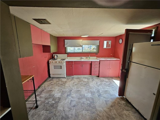 114 Leonard Rd, Washington Twp But, PA 16040 - kitchen featuring freestanding refrigerator, range with gas stovetop, a sink, red cabinetry, and stone finish floors