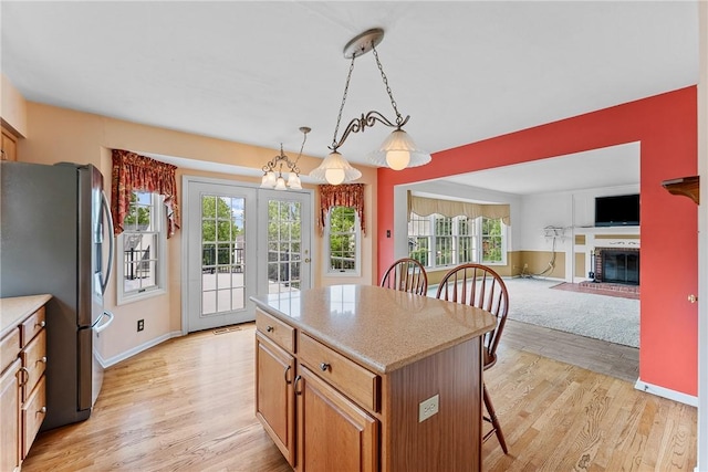 16 Mcbride Rd, North Strabane, PA 15317 - kitchen with stainless steel fridge with ice dispenser, light wood-style flooring, a kitchen bar, light countertops, and a brick fireplace