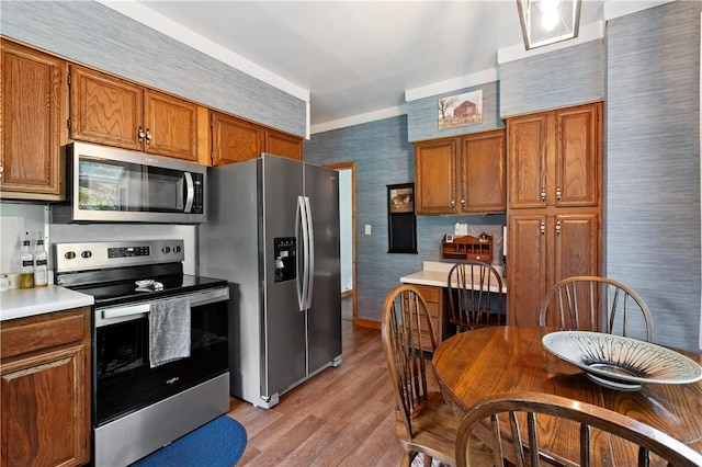 2418 Graceland Rd, Neshannock Twp, PA 16105 - kitchen featuring appliances with stainless steel finishes, light wood-type flooring, brown cabinetry, wallpapered walls, and light countertops