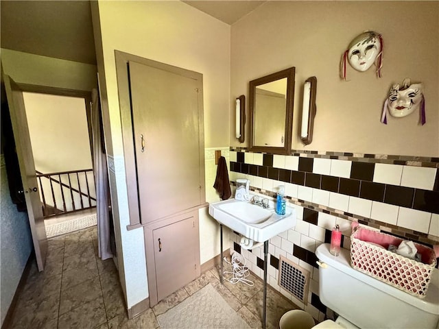509 N Mercer St, New Castle/1St, PA 16101 - bathroom featuring toilet, tile walls, a sink, and wainscoting