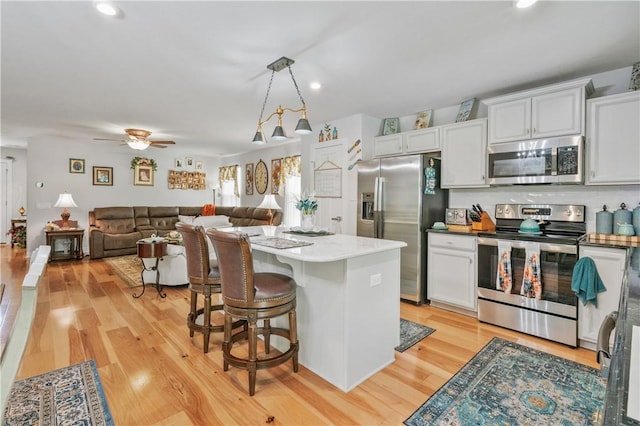 153 Olivia Dr, Center Twp Bea, PA 15061 - kitchen with appliances with stainless steel finishes, light wood-style floors, a kitchen island, a ceiling fan, and white cabinets