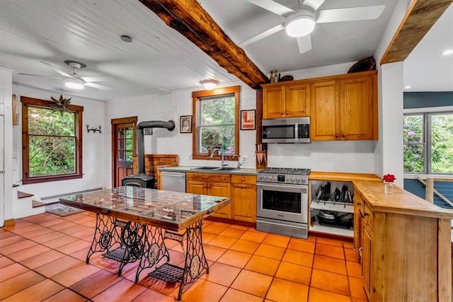 439 Pleasant Hill Rd, Allegheny Twp Wml, PA 15656 - kitchen featuring appliances with stainless steel finishes, a ceiling fan, a wood stove, a sink, and brown cabinetry