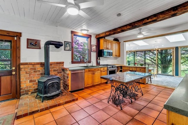 439 Pleasant Hill Rd, Allegheny Twp Wml, PA 15656 - kitchen with stainless steel appliances, ceiling fan, a skylight, a wood stove, and light tile patterned floors