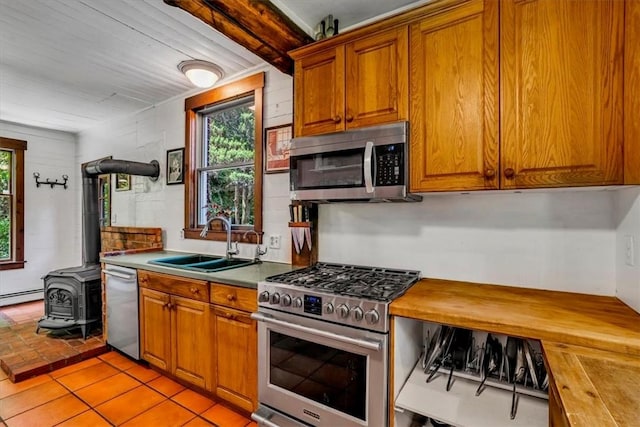 439 Pleasant Hill Rd, Allegheny Twp Wml, PA 15656 - kitchen featuring appliances with stainless steel finishes, a wood stove, wood counters, a sink, and brown cabinets