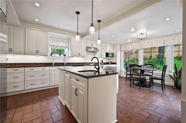 155 Westland Dr, Squirrel Hill, PA 15217 - kitchen featuring dark countertops, under cabinet range hood, stone tile flooring, white cabinets, and hanging light fixtures