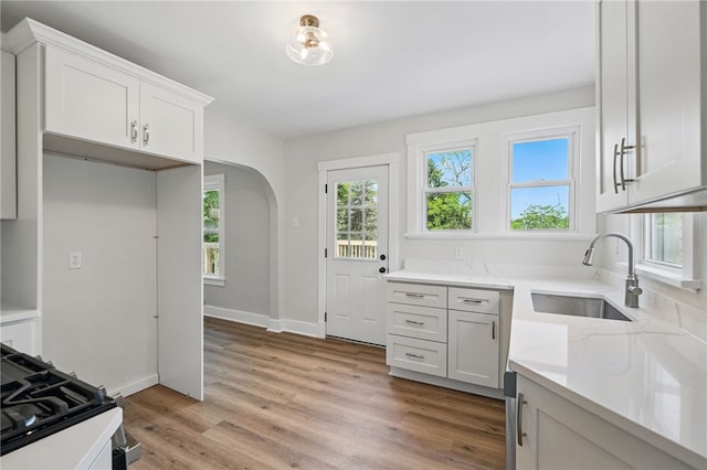 5241 Clarwin Ave, Ross Twp, PA 15229 - kitchen featuring a sink, arched walkways, light wood-style flooring, white cabinets, and baseboards