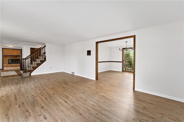 4117 Kellington Ct, Murrysville, PA 15668 - unfurnished living room with wood finished floors, stairway, a chandelier, and a fireplace