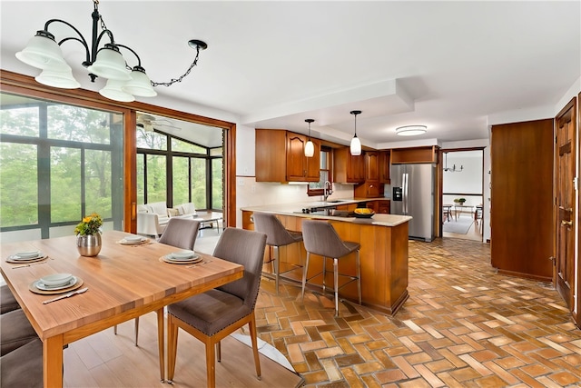 4117 Kellington Ct, Murrysville, PA 15668 - kitchen with stainless steel fridge with ice dispenser, a peninsula, brown cabinetry, hanging light fixtures, and a chandelier
