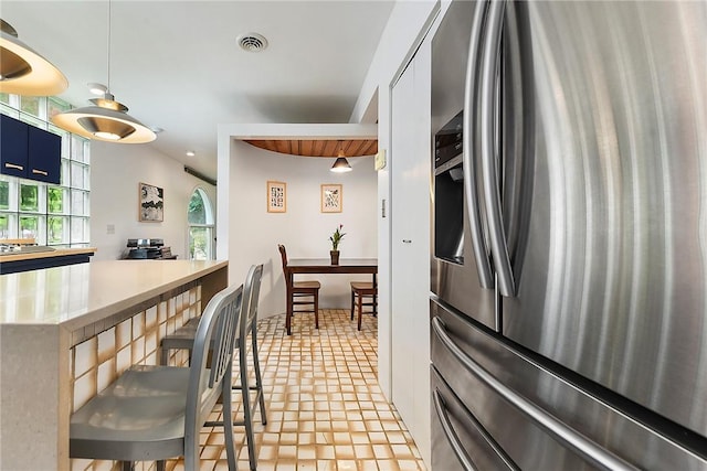 2219 Beechwood Blvd, Squirrel Hill, PA 15217 - kitchen with stainless steel refrigerator with ice dispenser, a kitchen bar, blue cabinetry, hanging light fixtures, and light countertops