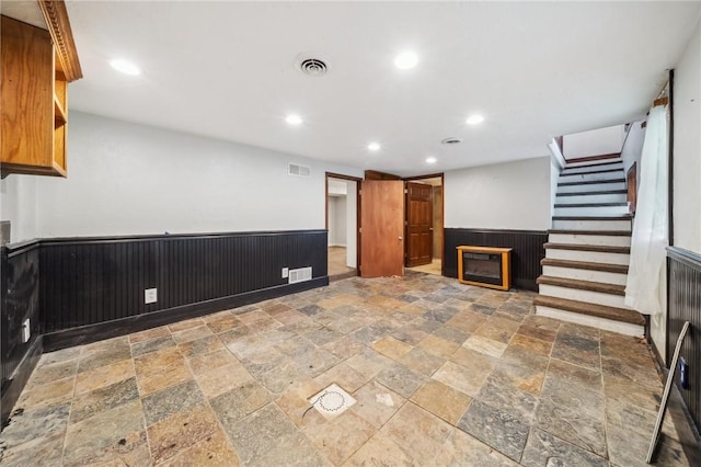 914 Western Ave, Jeannette, PA 15644 - unfurnished living room with stone tile floors, wainscoting, recessed lighting, stairway, and wooden walls